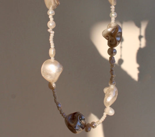 Unique mother of pearl shell necklace featuring a blend of small and large pearls, adding a distinctive touch to your look.